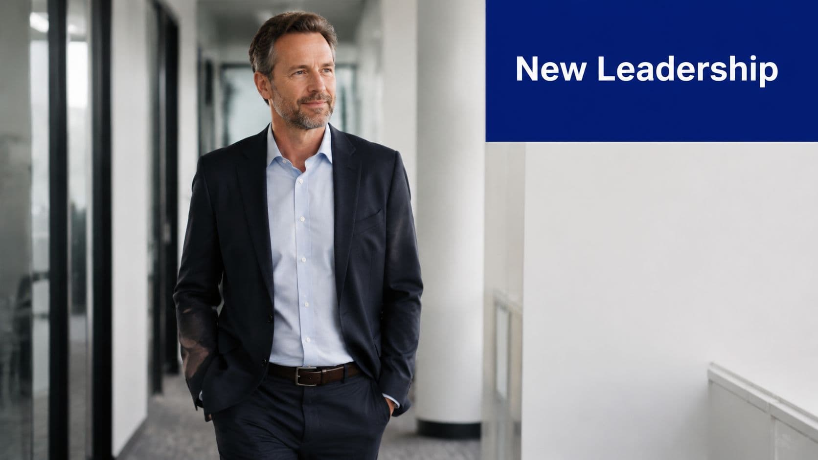 A professional man in a business suit walking down a modern office hallway for leadership communication.