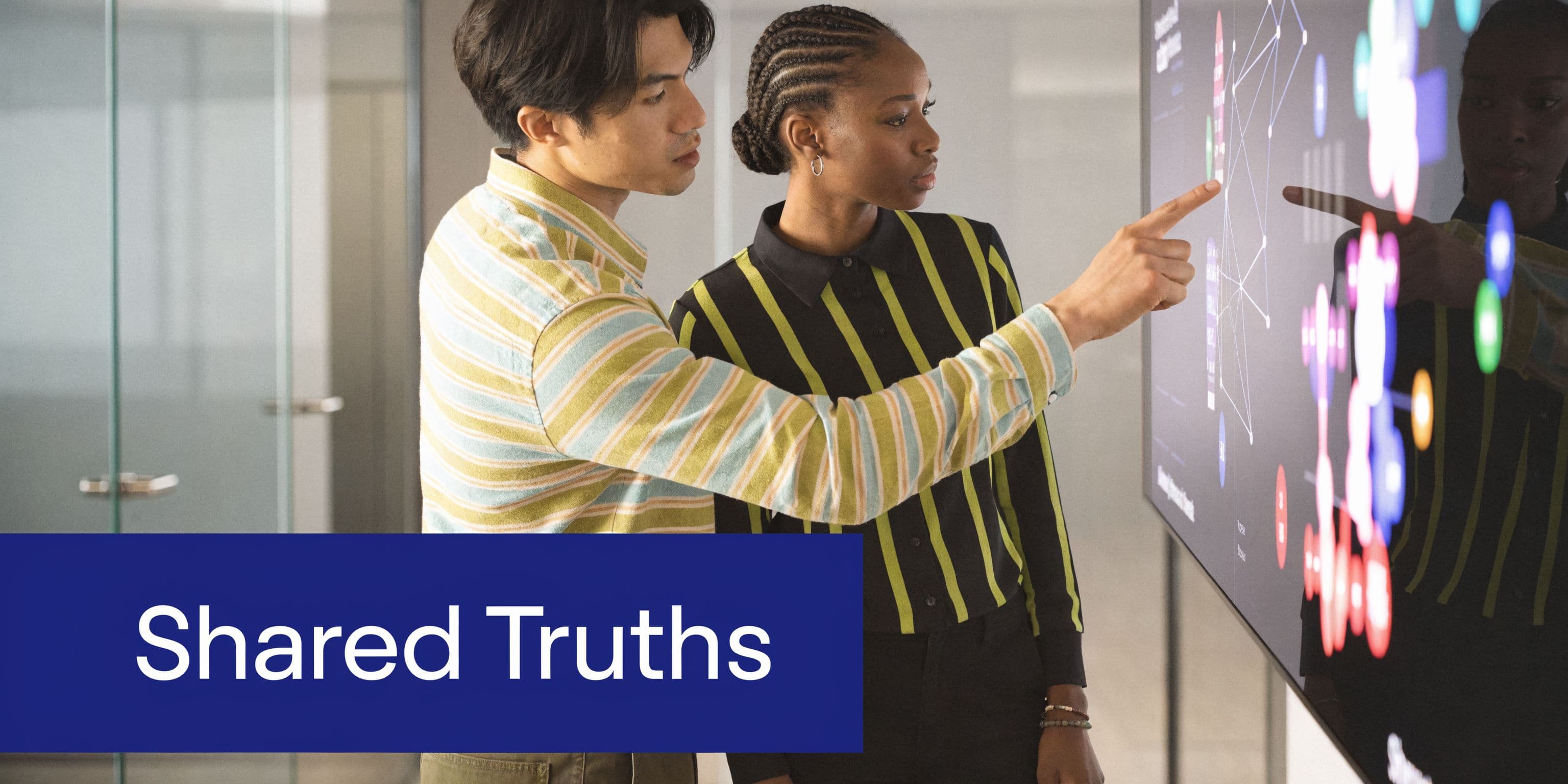 A professional man and woman collaborating on a data visualization screen in an office environment