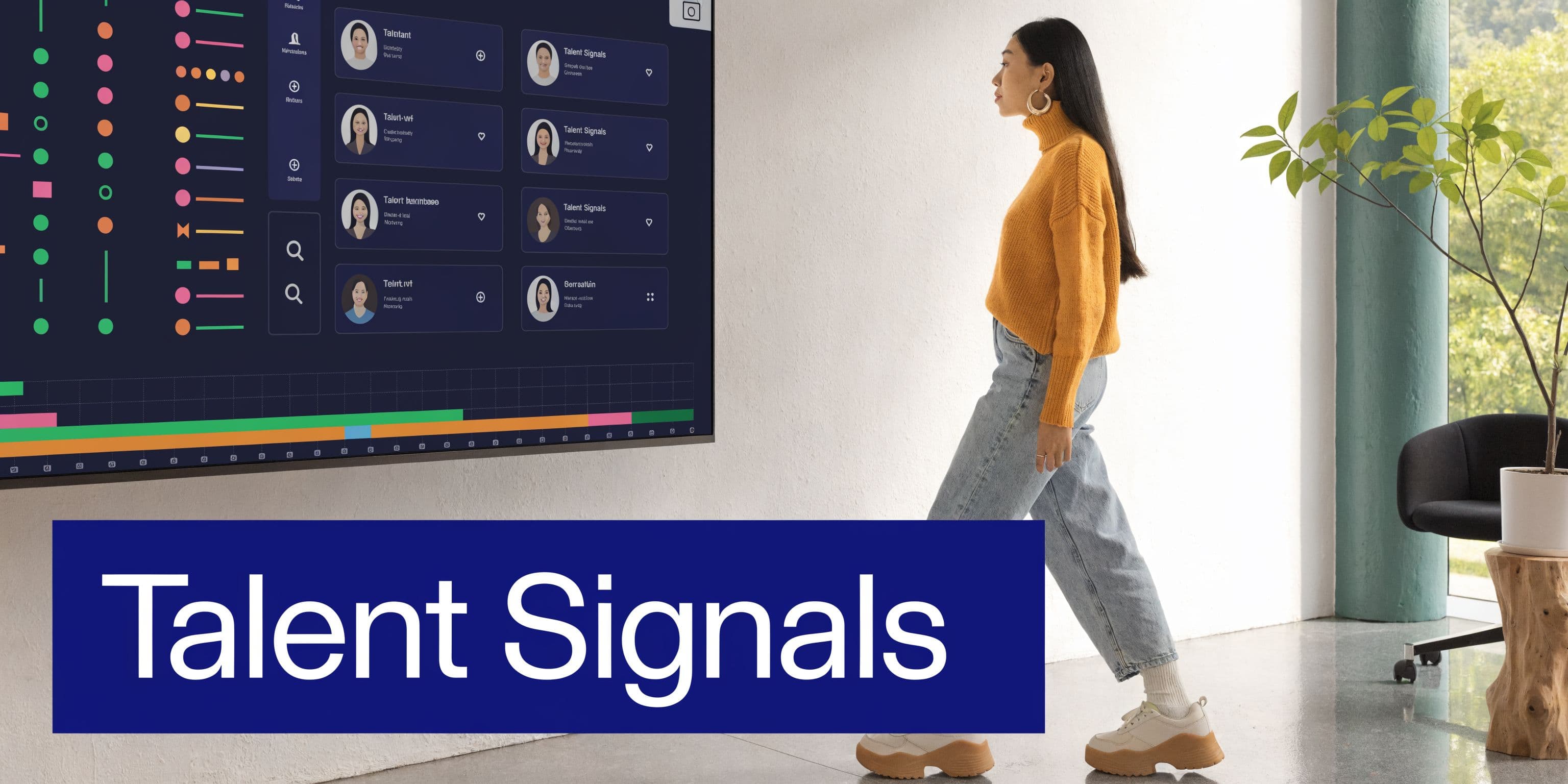 A woman walks past a large wall-mounted digital display showing talent management analytics and employee profiles.