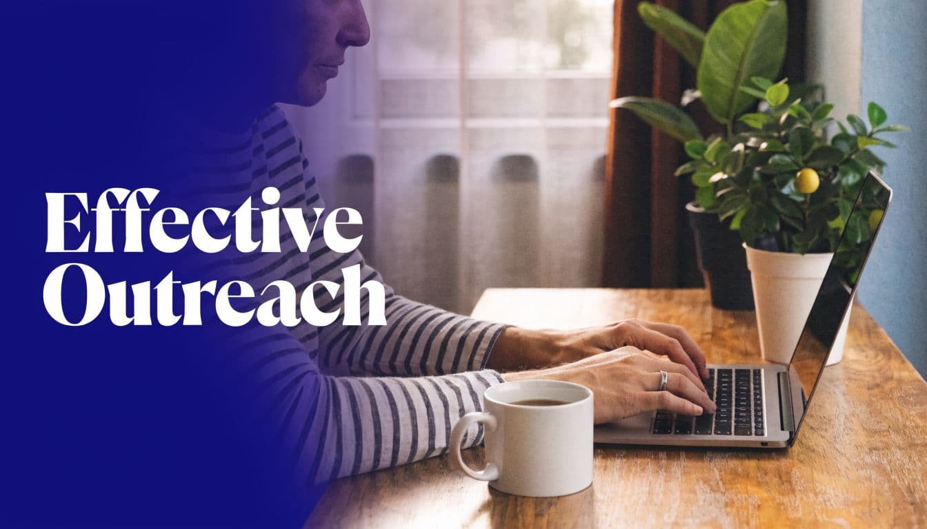 A person in a striped shirt typing on a laptop at a wooden table with a coffee cup.